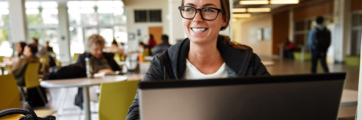 smiling woman with glasses at a laptop