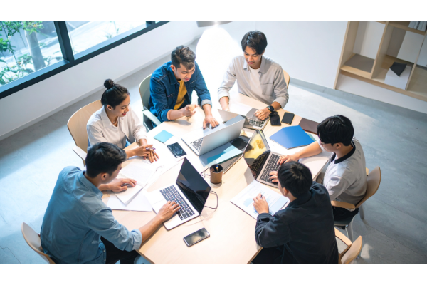 students sit around a table with laptops and books