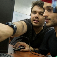 students in a lab, one pointing to a computer monitor