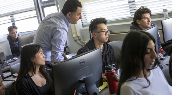 teacher and students at computers in a classroom
